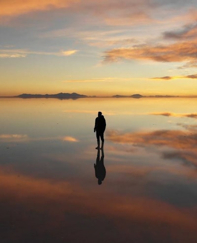 360 degree view of a man standing one a beach during a sunset