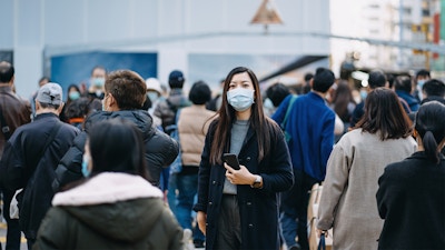 Woman in a protective mask, standing out from a crowd